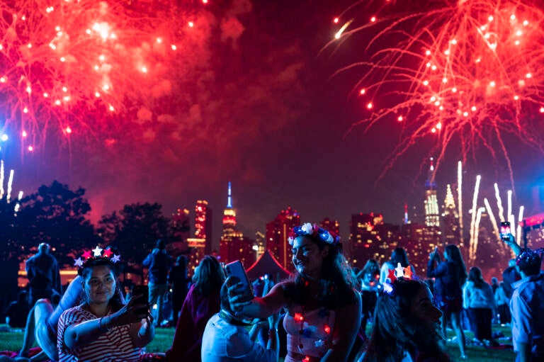 People smile as fireworks go off overhead.