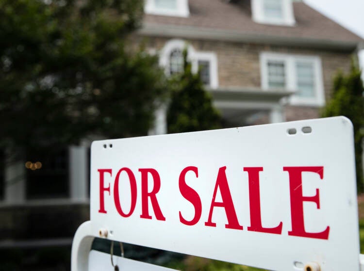 Warren Buffett Redlining A 'for sale' sign stands in front of a house