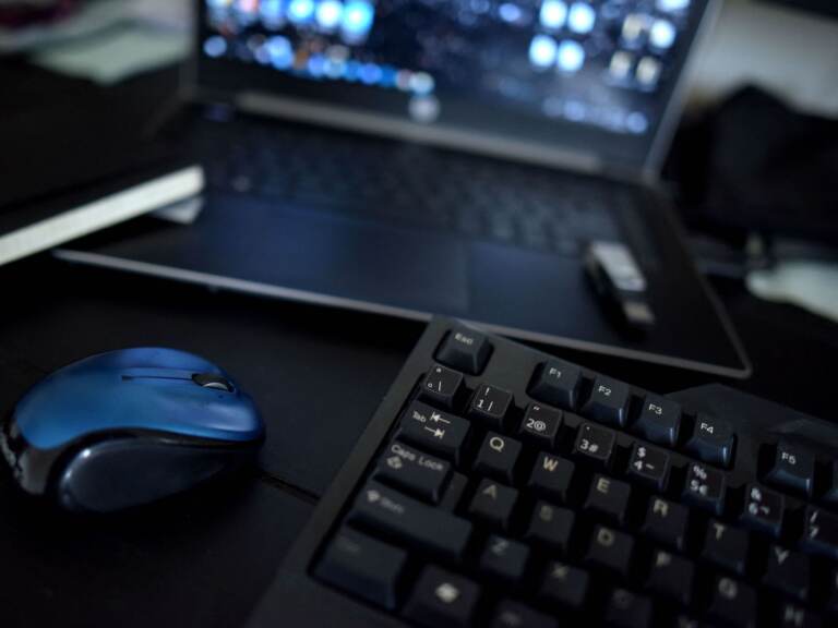 A home office desk with a keyboard, mouse, and laptop