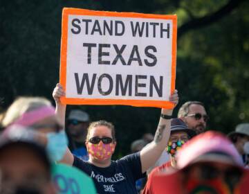 Demonstrators rally against anti-abortion and voter suppression laws at the Texas State Capitol, with one sign visible reading ''Stand with Texas Women''