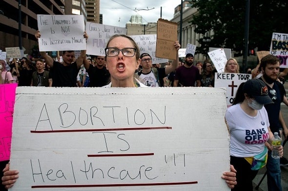 A doctor holds a sign that reads, 