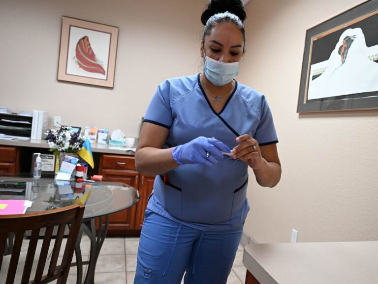 A medical assistant holds a patient's pregnancy test in her hands, while looking down at it.