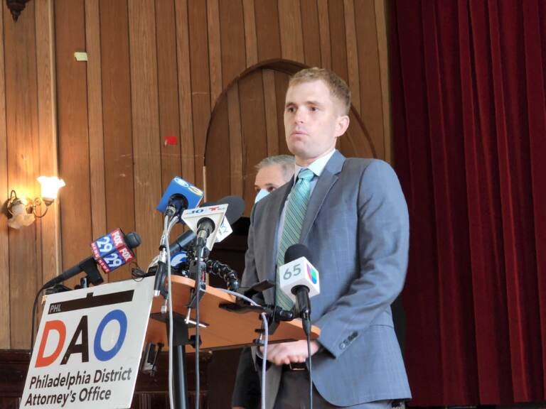 A man stands at a podium with a sign reading DAO in front of him.