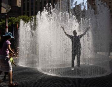 A person holds their arms up in a sprinkler.