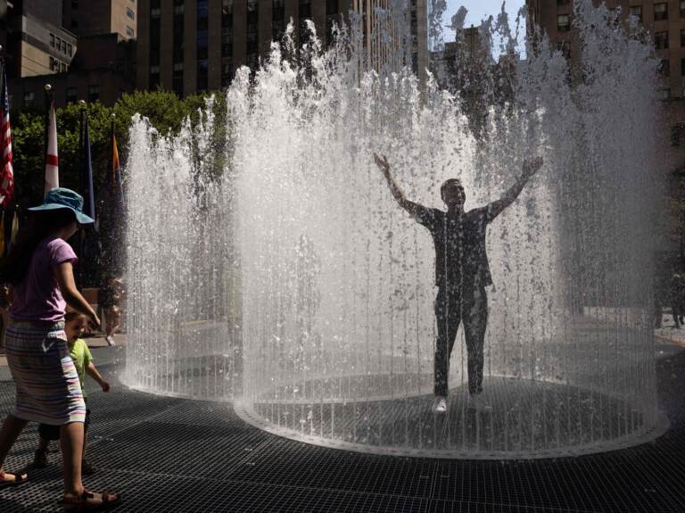 A person holds their arms up in a sprinkler.