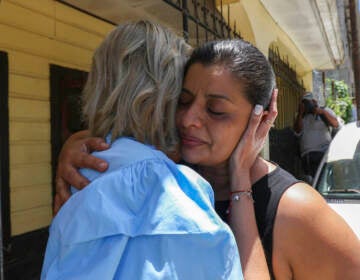 A woman cries as she is embraced by another person.