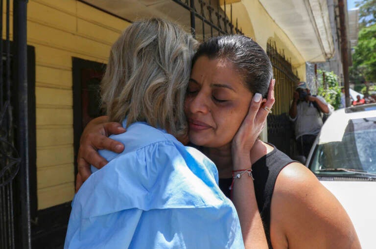 A woman cries as she is embraced by another person.