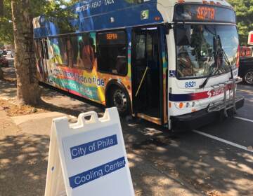 A bus that reads SEPTA on the front is parked by the curb. In front of it is a sign that advertises that it's a cooling center.