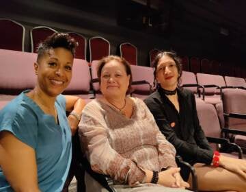 Three people pose, smiling, in a theater.