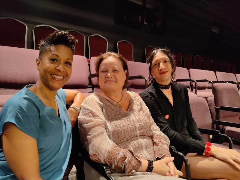 Three people pose, smiling, in a theater.