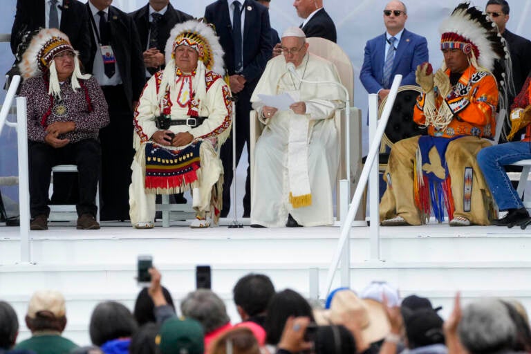 Pope Francis sits on stage with Indigenous leaders from Canada.