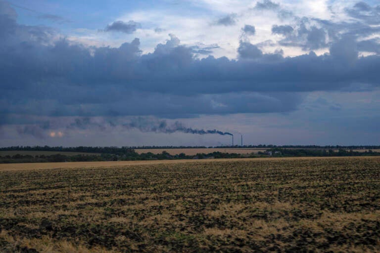 Grain fields backdropped by a power plant in Donetsk region, eastern Ukraine, Friday, July 22, 2022.