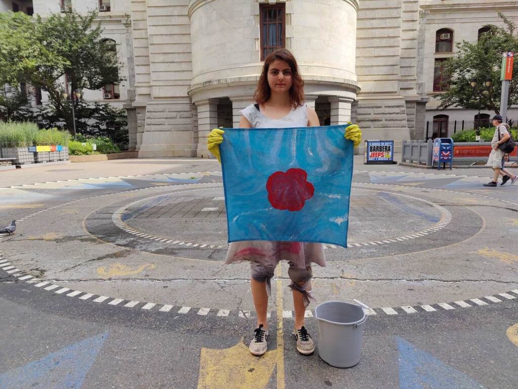 Shir Bassa holds up a blue cloth with a red flower in the center.