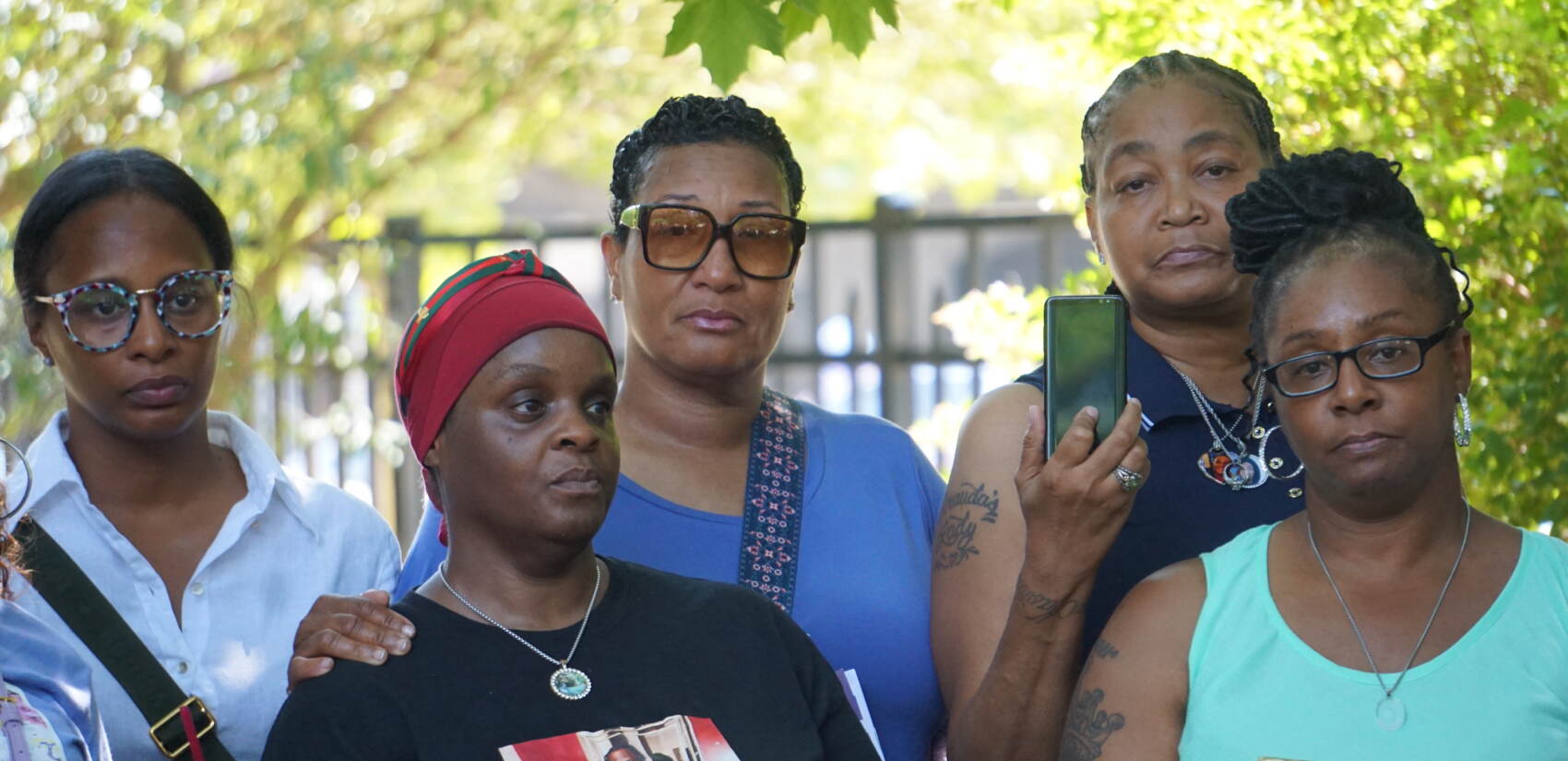 A group of women face the camera, looking in different directions at the exhibition, displayed off camera.
