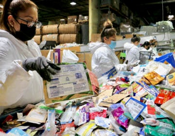 Workers sort items that require different recycling processes at a TerraCycle facility in New Brunswick. (Emma Lee/WHYY)