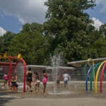 Families enjoy the sprinkler park at Ferko Playground