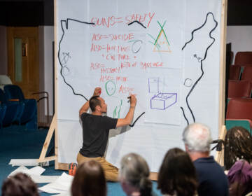 Makoto Hirano uses sketches out the themes of ''The Great American Gunshow'' during an interactive performance in Bloomsburg, Pa. (Elizabeth S. Gorbey)