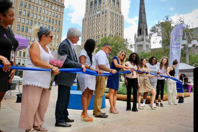 Laura Vargas, program manager of Philly HEALs Bereavement Program, cuts the ribbon for the opening of Philadelphia Overdose Memorial Garden at Thomas Paine Plaza. (Emma Lee/WHYY)