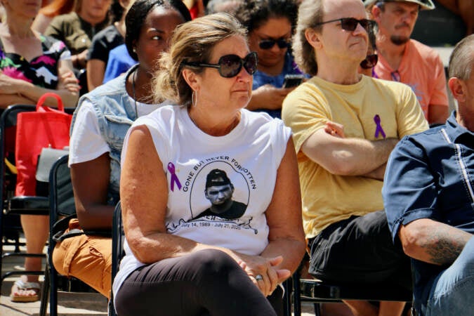 Mary Roth attends the opening ceremony of the Philadelphia Overdose Memorial Garden wearing a t-shirt with a photo of her son, Andrew, who died of an overdose in 2020. (Emma Lee/WHYY)