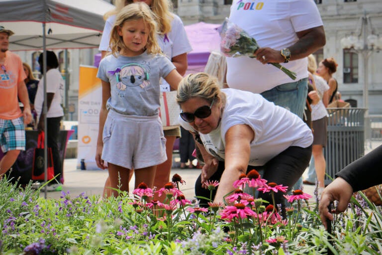 Mary Roth is comforted by her granddaughter, Stella Sniras, as she places a marker in the Philadelphia Overdose Memorial Garden for her son, Andrew Roth, who died of an overdose in July 2020.