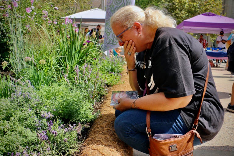 Terri Spina chokes back tears after placing a marker for her daughter in the Philadelphia Overdose Memorial Garden. (Emma Lee/WHYY)