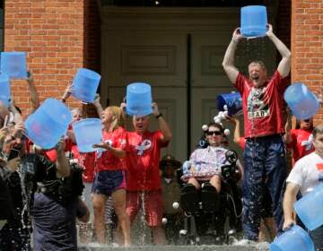 Massachusetts Gov. Charlie Baker, right center, and Lt. Gov. Karyn Polito, third from left, participate in the Ice Bucket Challenge with the man who inspired the event, Pete Frates, seated in center, to raise money for ALS research, at the Statehouse in Boston. Frates, who was stricken with amyotrophic lateral sclerosis, or ALS, died Monday, Dec. 9, 2019. He was 34. (AP Photo/Charles Krupa, File)