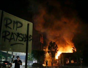 File photo: ''RIP Rayshard'' is spray painted on a street sign as as flames engulf a Wendy's restaurant during protests in Atlanta on Saturday, June 13, 2020. (AP Photo/Brynn Anderson)