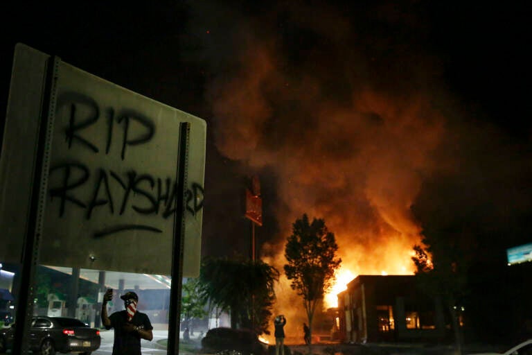 File photo: ''RIP Rayshard'' is spray painted on a street sign as as flames engulf a Wendy's restaurant during protests in Atlanta on Saturday, June 13, 2020. (AP Photo/Brynn Anderson)