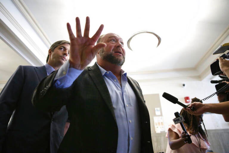 Alex Jones talks to media during a midday break during the trial at the Travis County Courthouse in Austin, Texas, Tuesday, July 26, 2022. An attorney for the parents of one of the children who were killed in the Sandy Hook Elementary School shooting told jurors that Jones repeatedly “lied and attacked the parents of murdered children” when he told his Infowars audience that the 2012 attack was a hoax. (Briana Sanchez/Austin American-Statesman via AP, Pool)