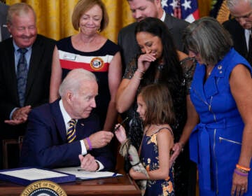 President Joe Biden gives the pen he used to sign the ''PACT Act of 2022'' to Brielle Robinson, daughter of Sgt. 1st Class Heath Robinson, who died of cancer two years ago, during a ceremony in the East Room of the White House, Wednesday, Aug. 10, 2022, in Washington. (AP Photo/Evan Vucci)