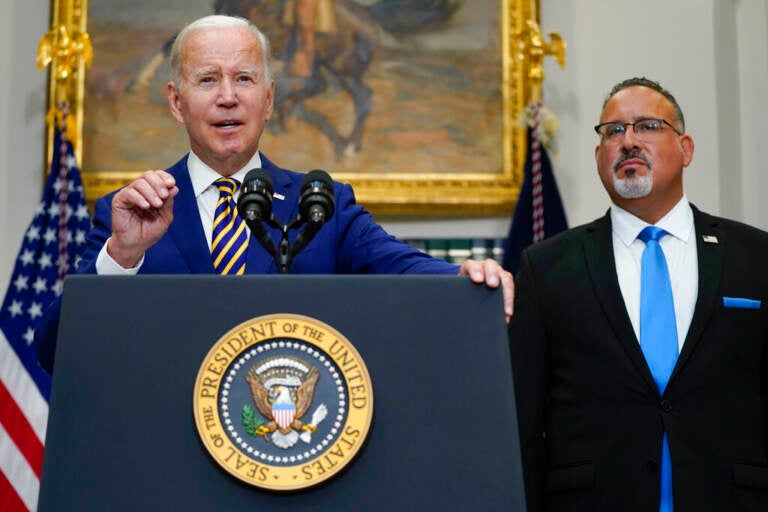 President Joe Biden speaks about student loan debt forgiveness in the Roosevelt Room of the White House, Wednesday, Aug. 24, 2022, in Washington. Education Secretary Miguel Cardona listens at right. (AP Photo/Evan Vucci)