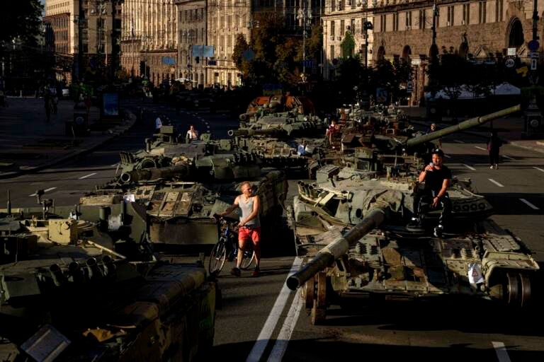 People walk around destroyed Russian military vehicles installed in downtown Kyiv, Ukraine, Wednesday, Aug. 24, 2022. (AP Photo/Evgeniy Maloletka)