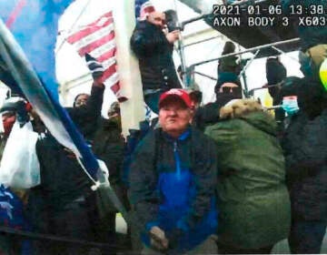 This image from police-worn body cam video and contained in the statement of facts supporting the arrest warrant for Howard Richardson, shows Richardson swinging a metal flagpole on Jan. 6, 2021, at the U.S. Capitol in Washington. (Department of Justice via AP)