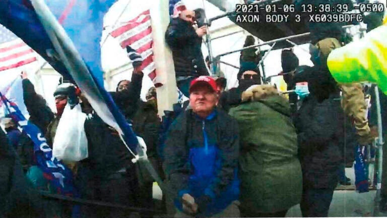 This image from police-worn body cam video and contained in the statement of facts supporting the arrest warrant for Howard Richardson, shows Richardson swinging a metal flagpole on Jan. 6, 2021, at the U.S. Capitol in Washington. (Department of Justice via AP)