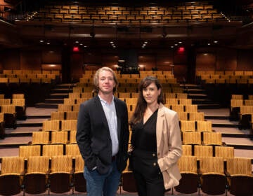 Tyler Dobrowsky and wife Taibi Magar pose with audience theater seats visible behind them.