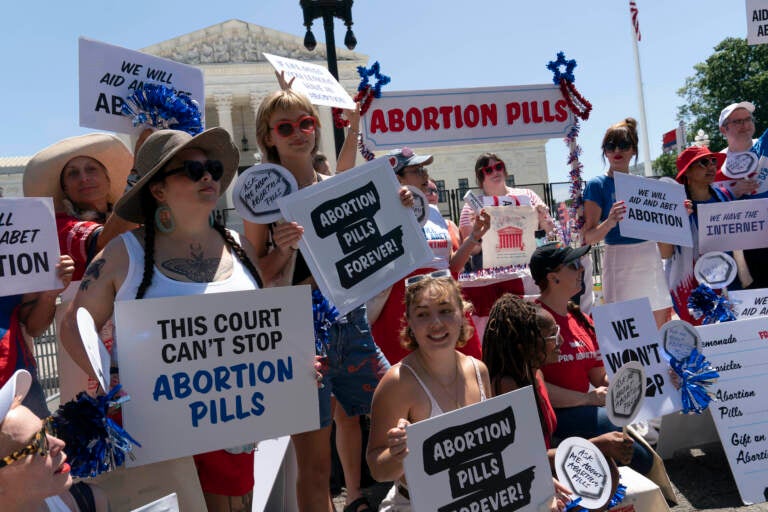 Abortion-rights activists setup an abortion pills educational booth as they protest outside the Supreme Court in Washington, Monday, July 4, 2022. The Supreme Court has ended constitutional protections for abortion that had been in place nearly 50 years, a decision by its conservative majority to overturn the court's landmark abortion cases. (AP Photo/Jose Luis Magana)