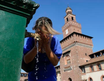 A woman cools-off at a public fountain of the Sforza Castle