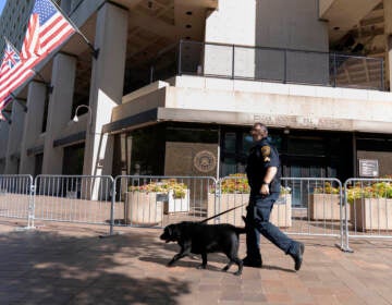 A Federal Bureau of Investigation police officer walks with his working dog outside Federal Bureau of Investigation building headquarters in Washington, Saturday, Aug. 13, 2022. (Jose Luis Magana/AP)