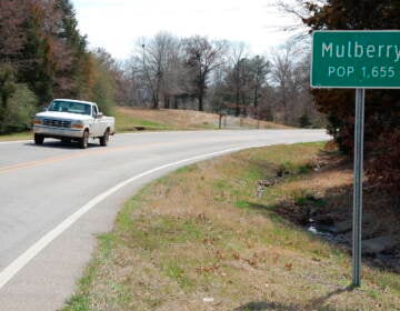 A truck drives near a population sign in Mulberry, Arkansas