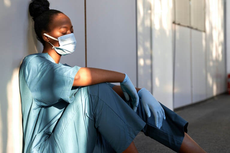 Tired exhausted nurse wears face mask blue uniform 
