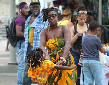 People dance at the Caribbean Fest in Philadelphia as others are visible in the background looking on.