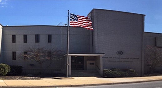 A view from outside of a building, with the U.S. flag flying in front of it.