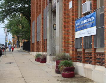 A sidewalk on the side of a red-brick school building.