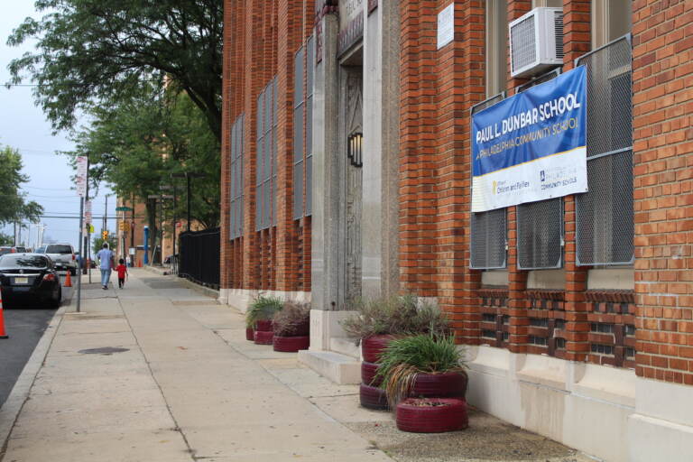 A sidewalk on the side of a red-brick school building.