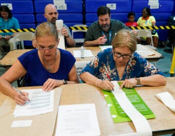 Two election employees check the tabulations made by voting equipment.