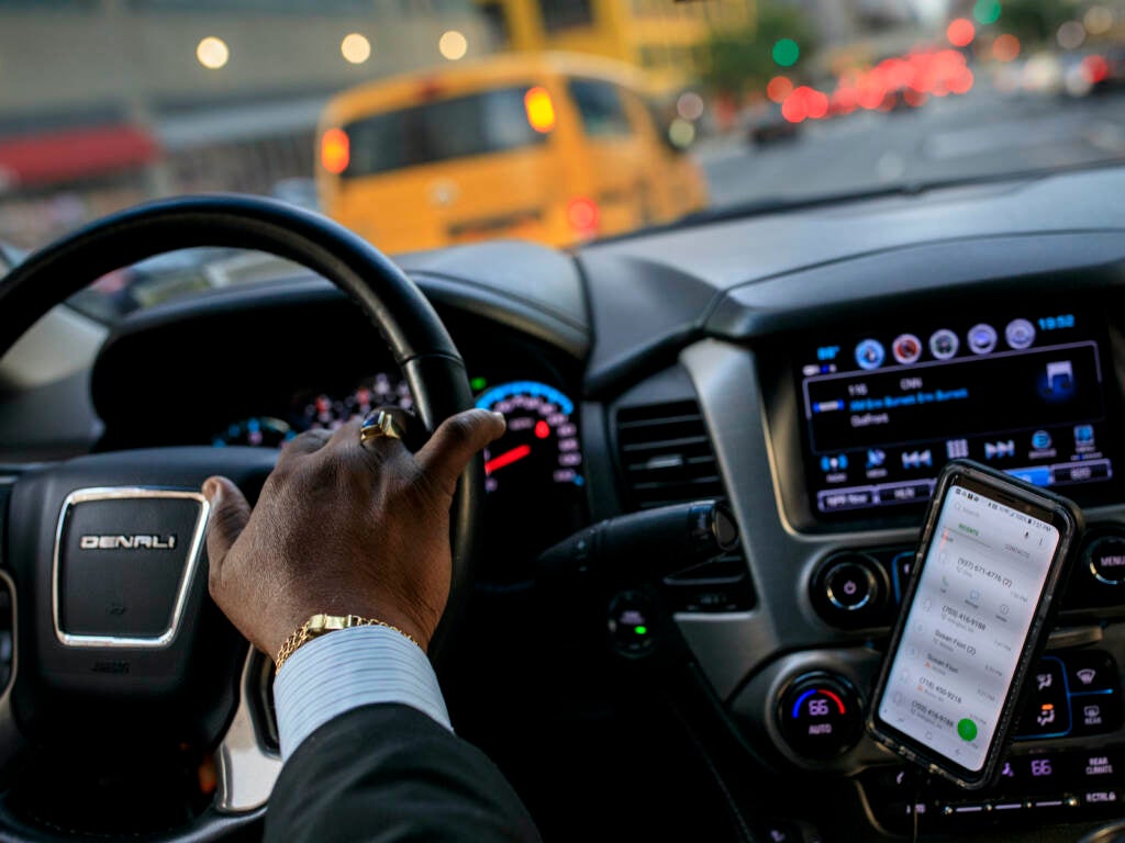 A close-up of a driver's hands on a steering wheel inside a car