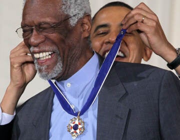 Bill Russell smiles as President Barack Obama is visible putting a medal around his neck.