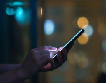 Closeup of woman's hand using a smartphone in the dark