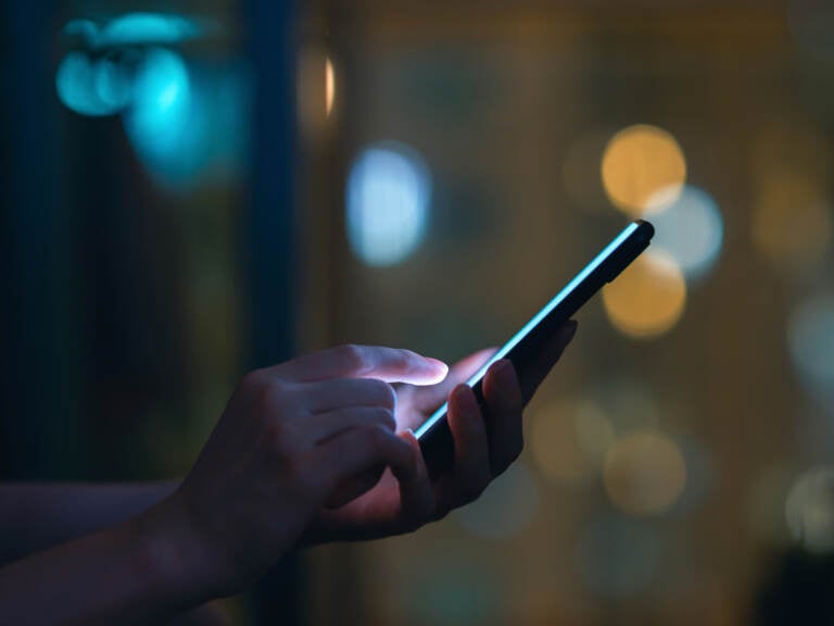 Closeup of woman's hand using a smartphone in the dark