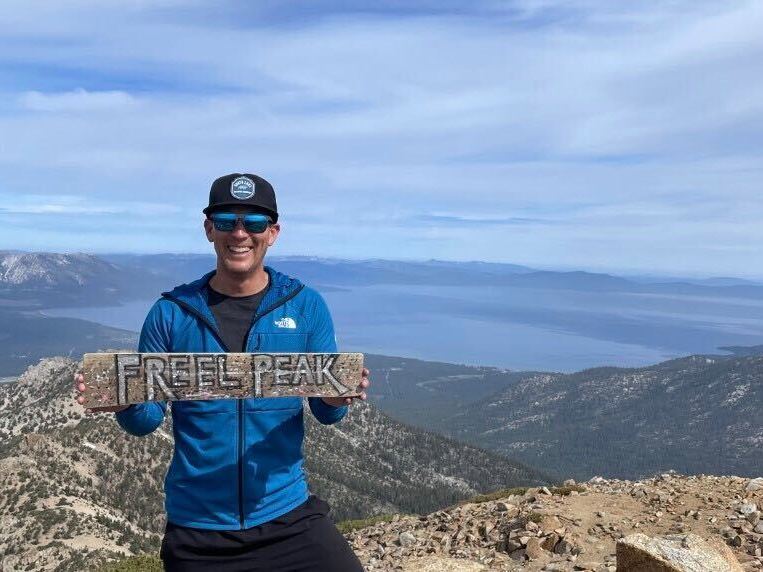 Allen Ishibashi holds up a sign on top of a mountain that reads, ''Freel Park''